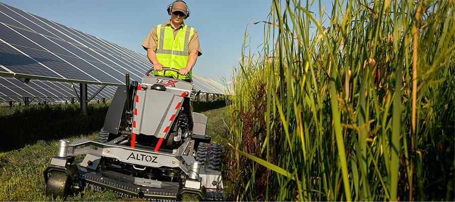 Altoz TSX tracked standing mower performing solar plant maintenance due to solar vegetation growth.